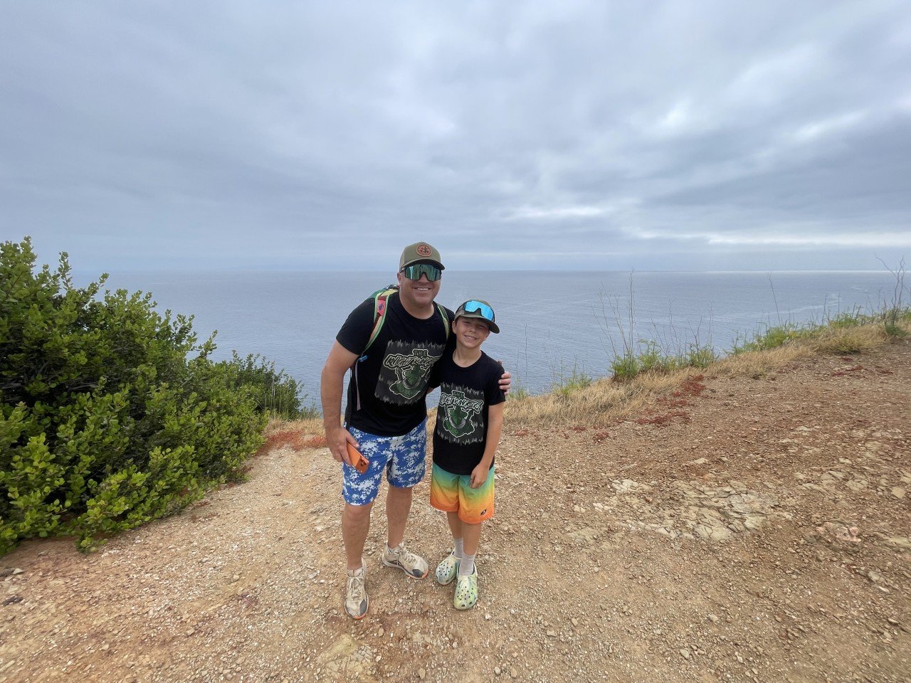 A dad and son in Knight Rangers shirts sharing a coastal view